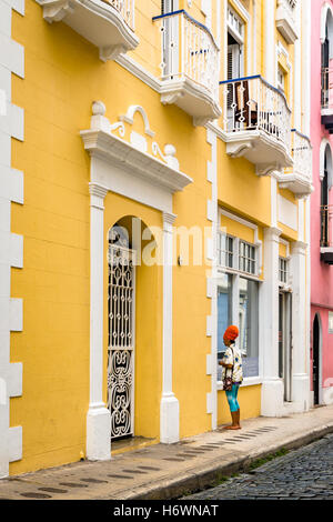 Lady in red head dress walking on Calle De La Cruz, Old San Juan (Puerto Rico) Stock Photo