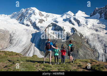 Hiking family looking to Monte Rosa from Gornergrat. Zermatt, Pennine Alps, Valais, Switzerland. Stock Photo
