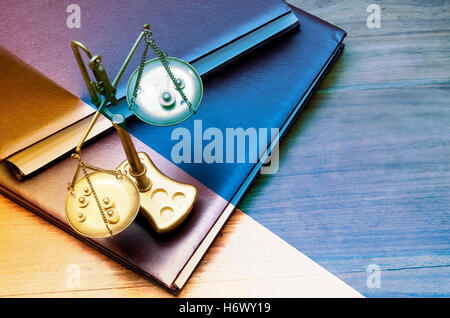 Mechanical golden weight scale, also laboratory balance, balance scale, or beam balance on law books Stock Photo