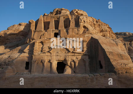 Ancient rock cut monument carved into pink sandstone cliff ( 25-75 AD ) known as the 'Obelisk Tomb' crowned with four elongated pyramids that represent Nefesh, Nabatean signs commemorating the deceased located at Petra the ancient capital of the Nabatean Kingdom in the southwestern desert of Jordan Stock Photo