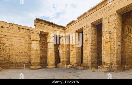 The peristyle court of Habu Temple with different types of columns and stone walls covered with ancient hieroglyphs and Egypt Stock Photo