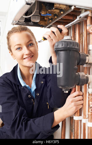 Female Plumber Working On Central Heating Boiler Stock Photo