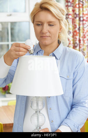 Woman Putting Low Energy LED Lightbulb Into Lamp At Home Stock Photo