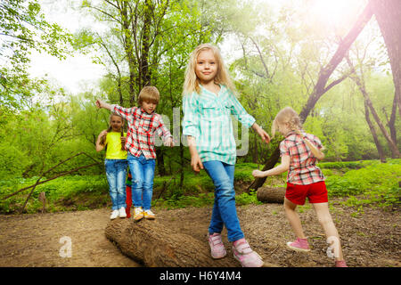 Happy kids walking on log and balancing in forest Stock Photo