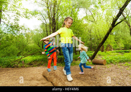 Kids standing on a log and balancing in the forest Stock Photo