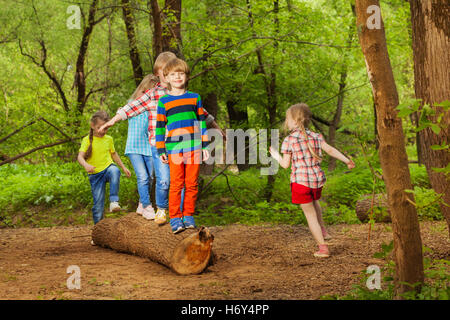 Cute little kids walking on log of tree in park Stock Photo