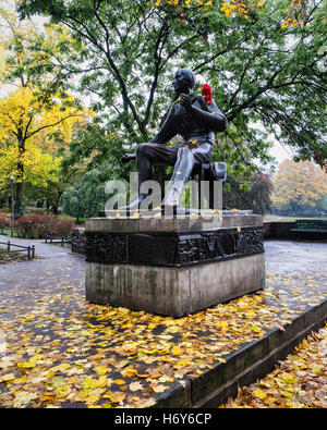 Heinrich Heine statue holding a bunch of red carnations in Autumn. Bronze sculpture of the poet Weinbergsweg Park, Mitte, Berlin Stock Photo