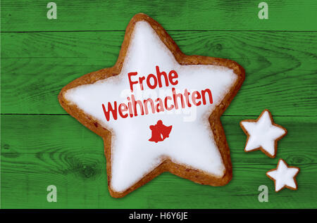 Frohe Weihnachten (in german Merry Christmas) cinnamon star on green wood background. Stock Photo