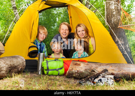 Happy young family relaxing inside tent in woods Stock Photo