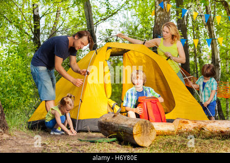 Happy family putting up a tent together in woods Stock Photo