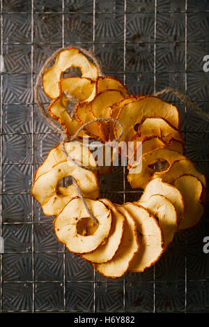 Dried apple slices hanging on string with dark metal backdrop Stock Photo