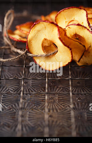 Dried apple slices hanging on string with dark metal backdrop Stock Photo