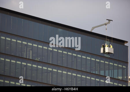 Window cleaner in Basket commercial   Industrial professional cleaners exterior dangling cradle outside lift crane rooftop high Stock Photo