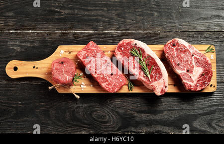 Fresh raw Prime Black Angus beef steaks on wooden board: Tenderloin, Denver Cut, Striploin, Rib Eye Stock Photo