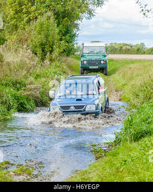 A 4x4 and a Landrover Defender 90 crossing, or fording, a stream or river Stock Photo