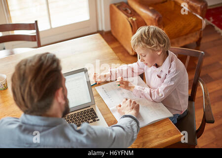 Father helping son with homework in home office Stock Photo