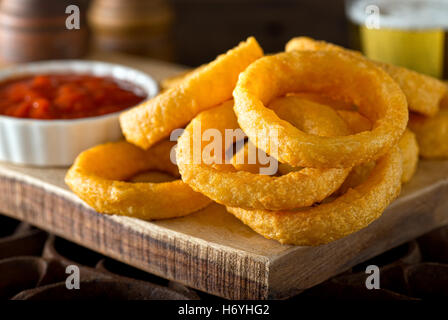 Delicious pub style onion rings with ketchup and beer. Stock Photo