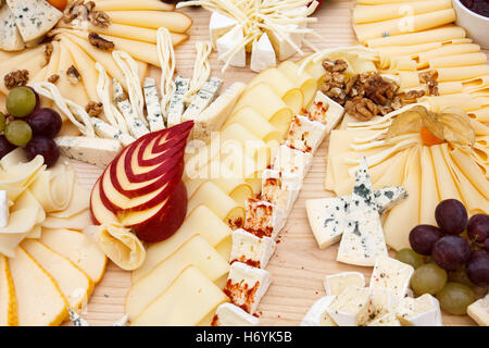 Mixed cheeses on light wooden board. Stock Photo