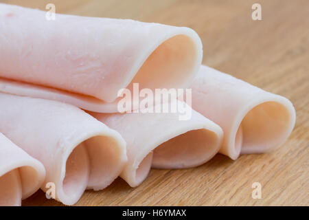 Rolled slices of ham on a wood surface. Stock Photo