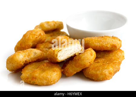 Pile of golden deep-fried battered chicken nuggets with empty bowl, isolated on white. Stock Photo