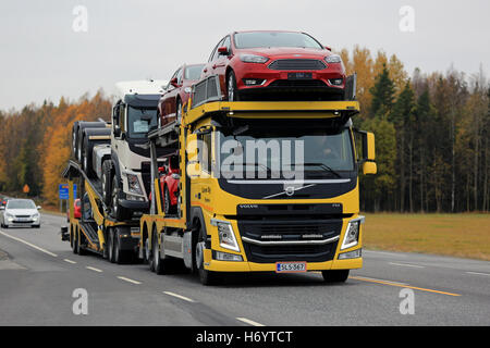 KAARINA, FINLAND - OCTOBER 14, 2016: Yellow Volvo FM car transporter hauls new cars along highway in autumn. Stock Photo