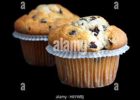 Two light chocolate chip muffins in wax liner on black. Stock Photo