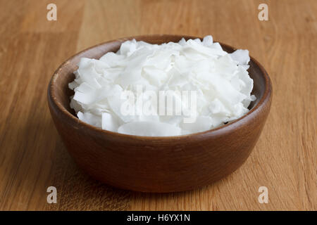 Dark wood bowl of shaved coconut on wood table. Stock Photo