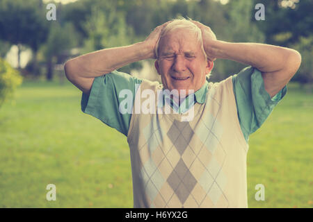 Elderly man holding his head. Stock Photo