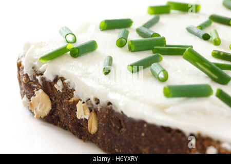 Cut fresh chives on thickly spread cream cheese on dark health bread. Stock Photo