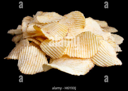 Ridged fried potato crisps on black. Stock Photo