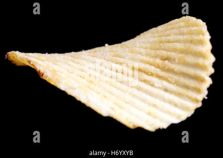 Single ridged fried potato crisp on black. Stock Photo