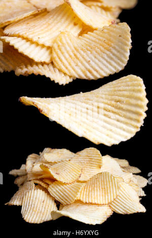 Collage of ridged fried potato crisps on black. Stock Photo