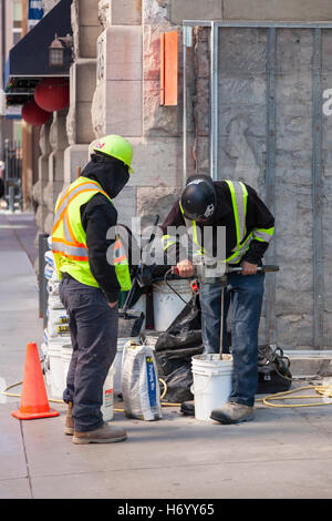A construction worker mixes cement while a coworker watches in Ottawa, Ontario, Canada. Stock Photo
