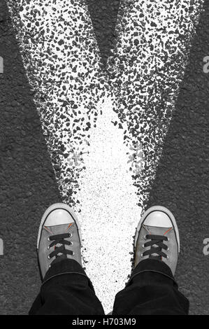 Sneakers stand on asphalt pavement with the white road marking lines Stock Photo