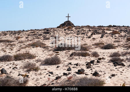 Fuerteventura, Canary Islands, North Africa, Spain: a tomb with a pile of stones and a wooden cross in the desert landscape near El Cotillo town Stock Photo