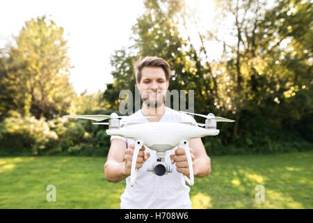 Young hipster man holding drone. Sunny green nature. Stock Photo