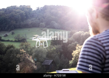 Unrecognizable hipster man with flying drone. Sunny nature. Stock Photo