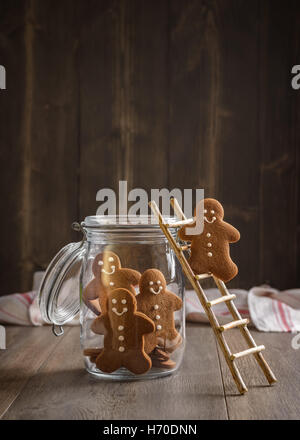 Gingerbread man on rustic ladder climbing into cookie jar Stock Photo