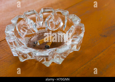 Dirty ashtray with cigarette butts on the table Stock Photo