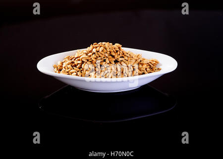 Roasted Salted Sunflower Seeds in a white plate on a black background Stock Photo