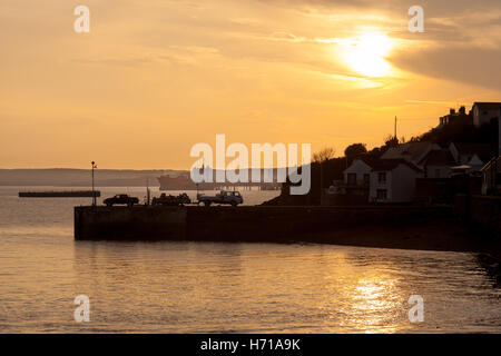 Fishermen landing a catch on the quay at Milford Haven with an oil tanker in the background. Stock Photo