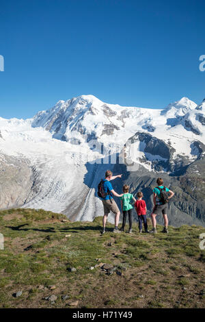 Hiking family looking to Monte Rosa from Gornergrat. Zermatt, Pennine Alps, Valais, Switzerland. Stock Photo
