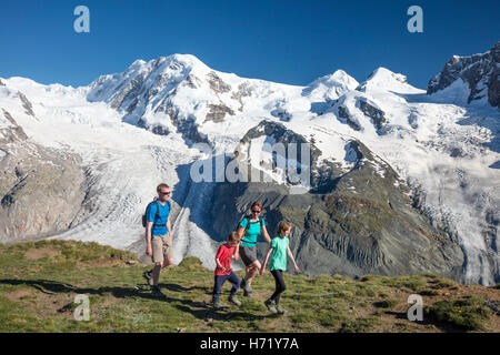 Family hiking beneath Monte Rosa, from Gornergrat. Zermatt, Pennine Alps, Valais, Switzerland. Stock Photo
