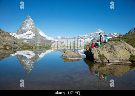 Hiking family and Matterhorn reflected in the Riffelsee. Zermatt, Pennine Alps, Valais, Switzerland. Stock Photo