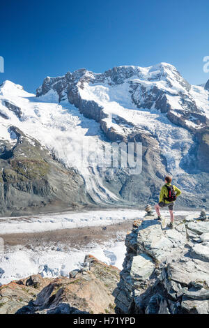 Hiker looking over Gorner Glacier and Monte Rosa from Gornergrat. Zermatt, Pennine Alps, Valais, Switzerland. Stock Photo