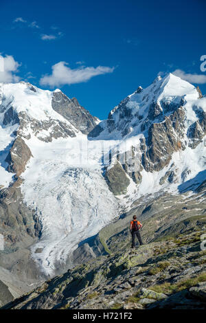 Hiker beneath Piz Bernina and Piz Rosbeg. Fuorcla Surlej, Silvaplana, Berniner Alps, Graubunden, Switzerland. Stock Photo