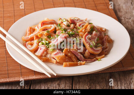 fried pig ears with sesame seeds and green onions close-up on a plate on the table. Horizontal Stock Photo