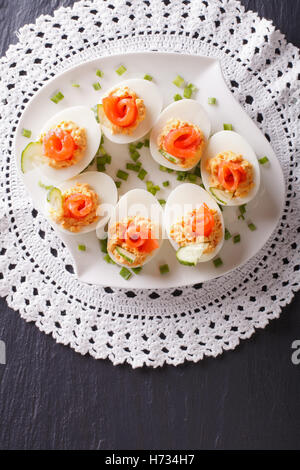 Eggs stuffed with salmon, cheese and cucumber on a table. vertical view from above Stock Photo