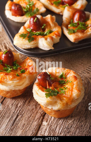Freshly baked muffins with sausage, cheese and onion close-up on the table. Vertical Stock Photo