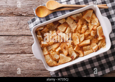 Fresh-baked English bread pudding with raisins in baking dish on the table. Horizontal view from above Stock Photo
